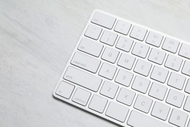 Photo of Modern wireless keyboard on white wooden table, above view. Space for text