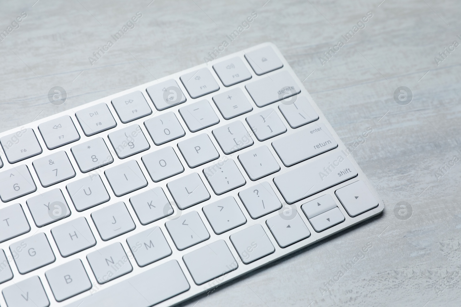 Photo of Modern wireless keyboard on white wooden table, closeup