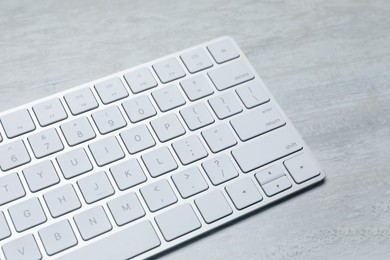 Photo of Modern wireless keyboard on white wooden table, closeup