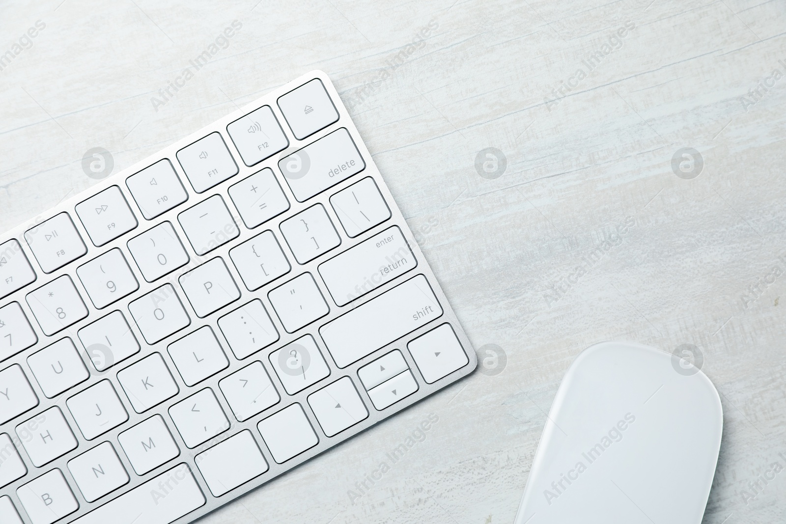 Photo of Modern wireless keyboard and mouse on white wooden table, top view