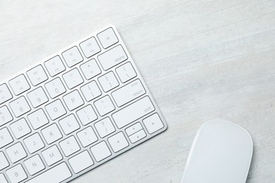 Photo of Modern wireless keyboard and mouse on white wooden table, top view