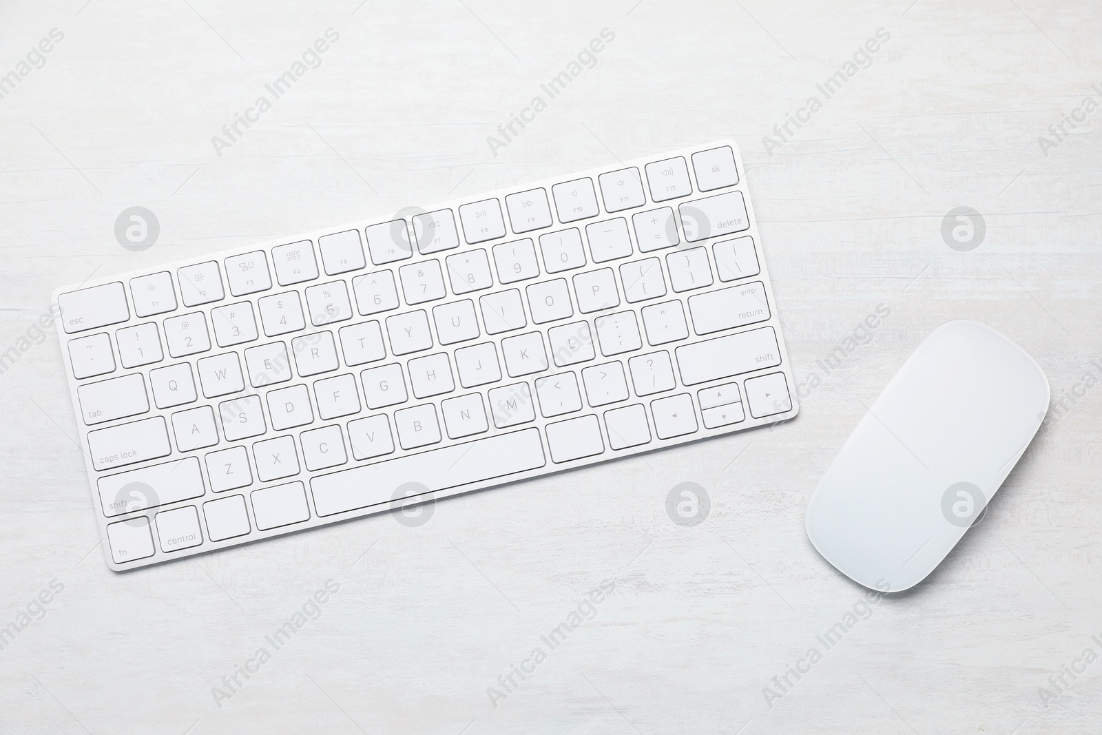 Photo of Modern wireless keyboard and mouse on white wooden table, top view