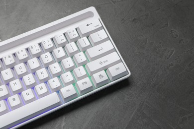 Photo of Modern white keyboard with RGB lighting on grey table, above view. Space for text