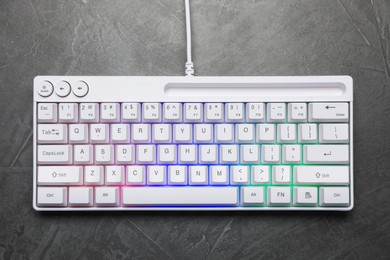 Photo of Modern white keyboard with RGB lighting on grey table, top view