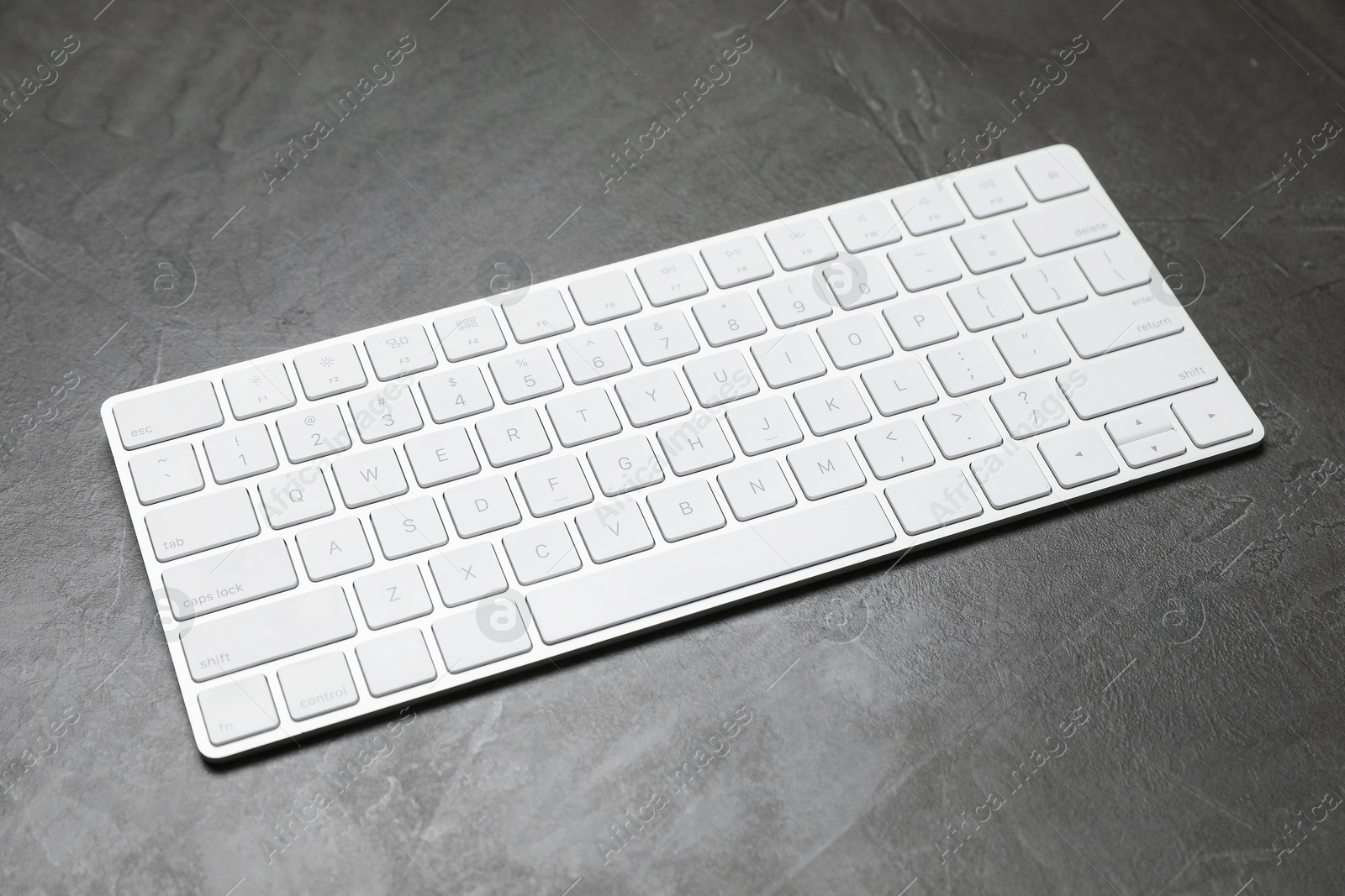 Modern white wireless keyboard on grey table Photo of Modern white wireless keyboard on grey table