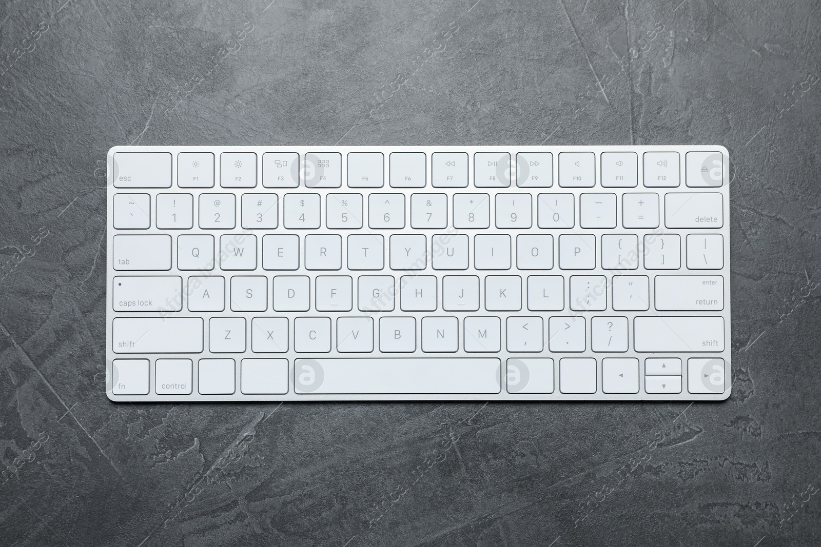 Modern white wireless keyboard on grey table, top view Photo of Modern white wireless keyboard on grey table, top view