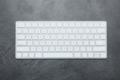 Photo of Modern white wireless keyboard on grey table, top view