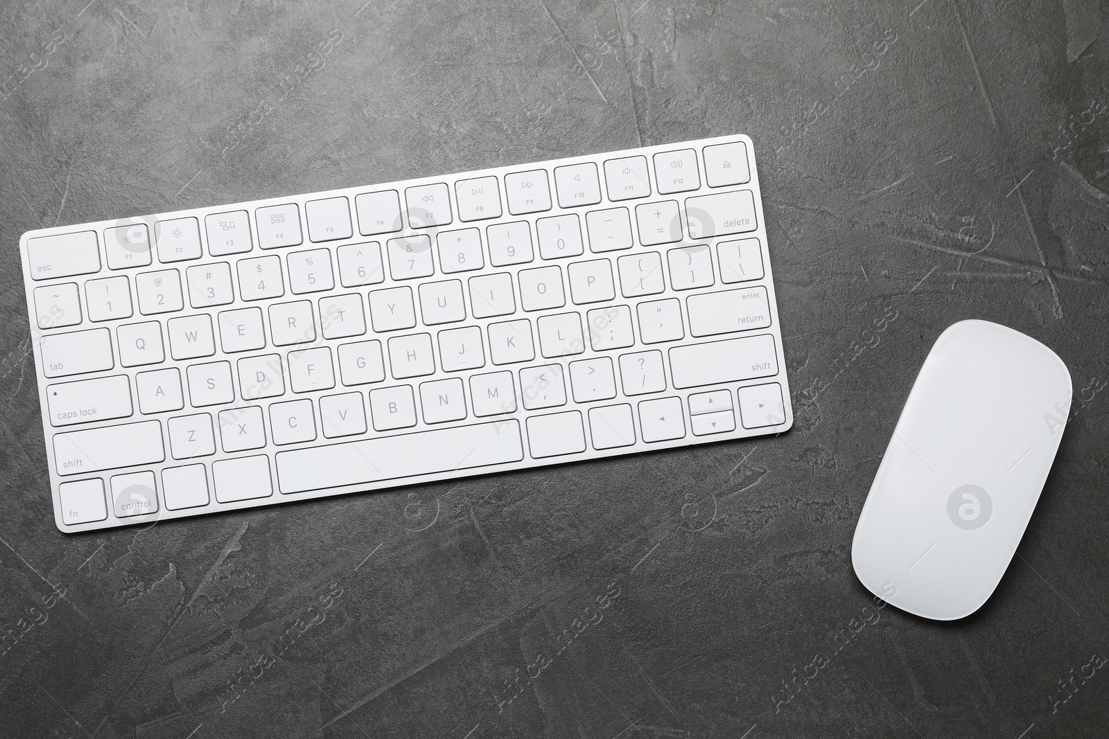 Modern white wireless keyboard and mouse on grey table, top view Photo of Modern white wireless keyboard and mouse on grey table, top view