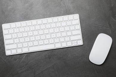 Photo of Modern white wireless keyboard and mouse on grey table, top view