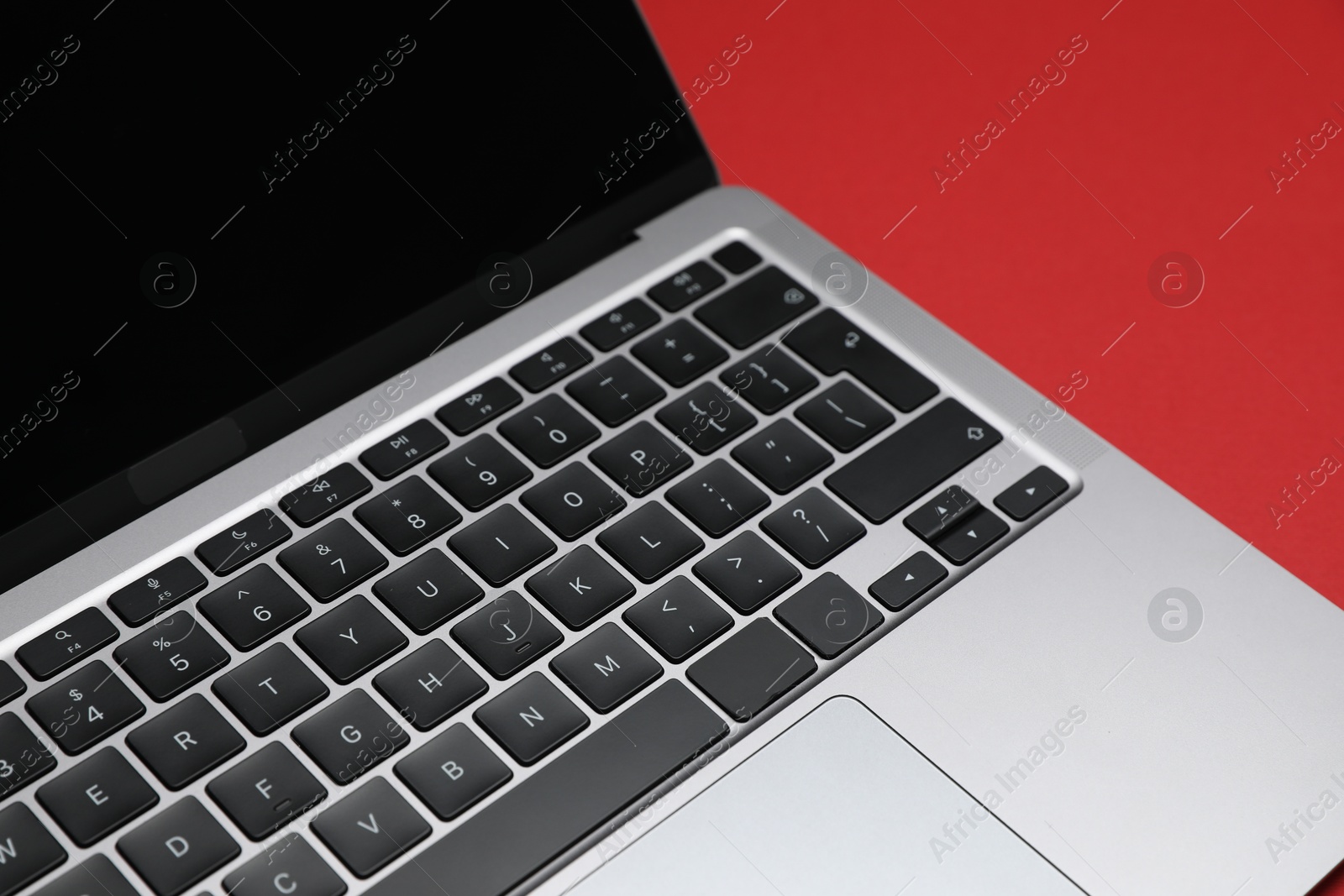 Modern laptop with keyboard on red background, closeup Photo of Modern laptop with keyboard on red background, closeup