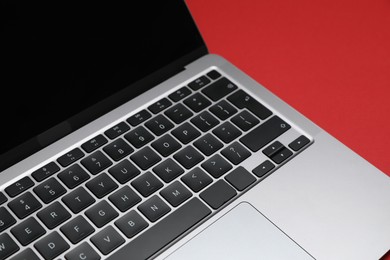 Photo of Modern laptop with keyboard on red background, closeup