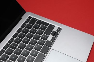 Photo of Modern laptop with keyboard on red background, closeup