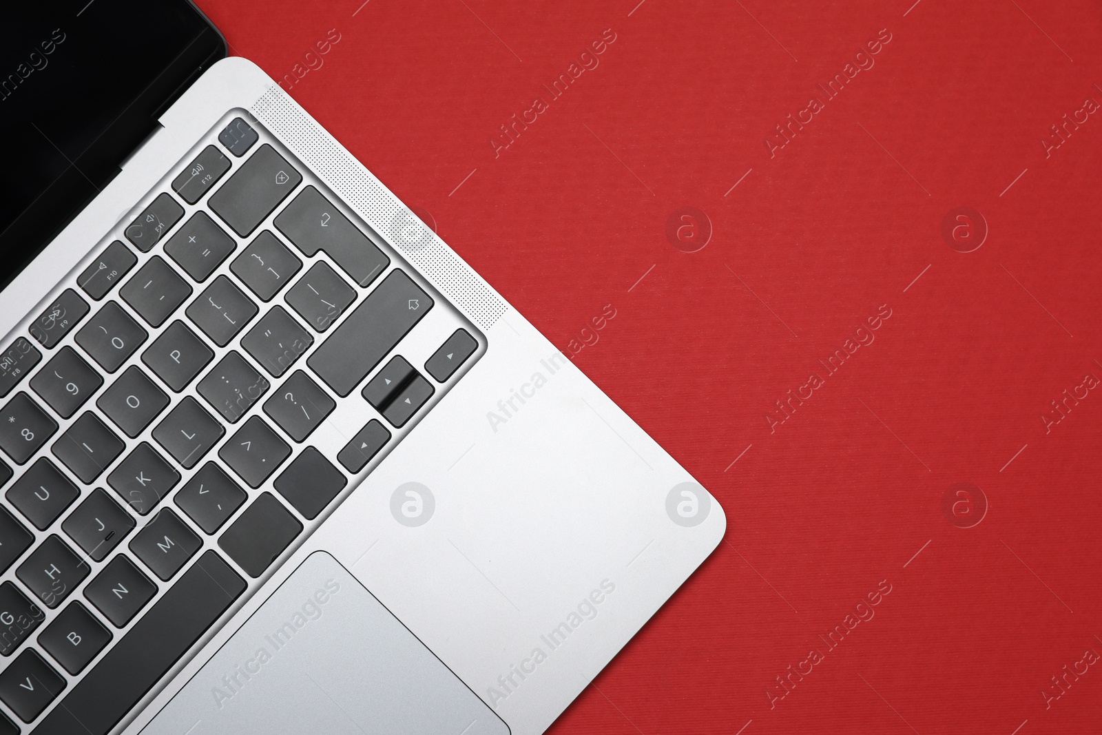 Modern laptop with keyboard on red background, top view. Space for text Photo of Modern laptop with keyboard on red background, top view. Space for text