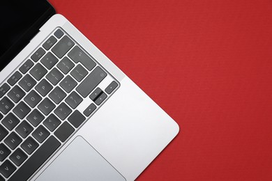 Photo of Modern laptop with keyboard on red background, top view. Space for text