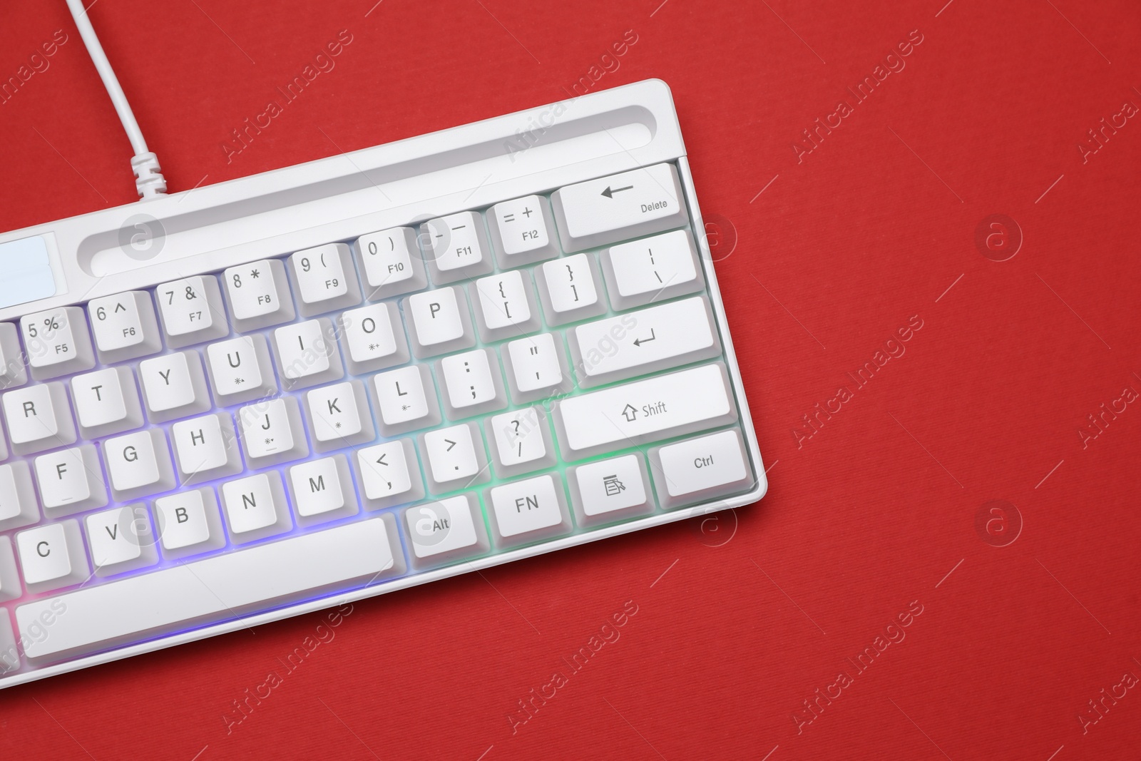 Modern white keyboard with RGB lighting on red background, top view. Space for text Photo of Modern white keyboard with RGB lighting on red background, top view. Space for text