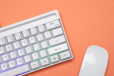 Photo of Modern white keyboard with RGB lighting and mouse on orange background, top view