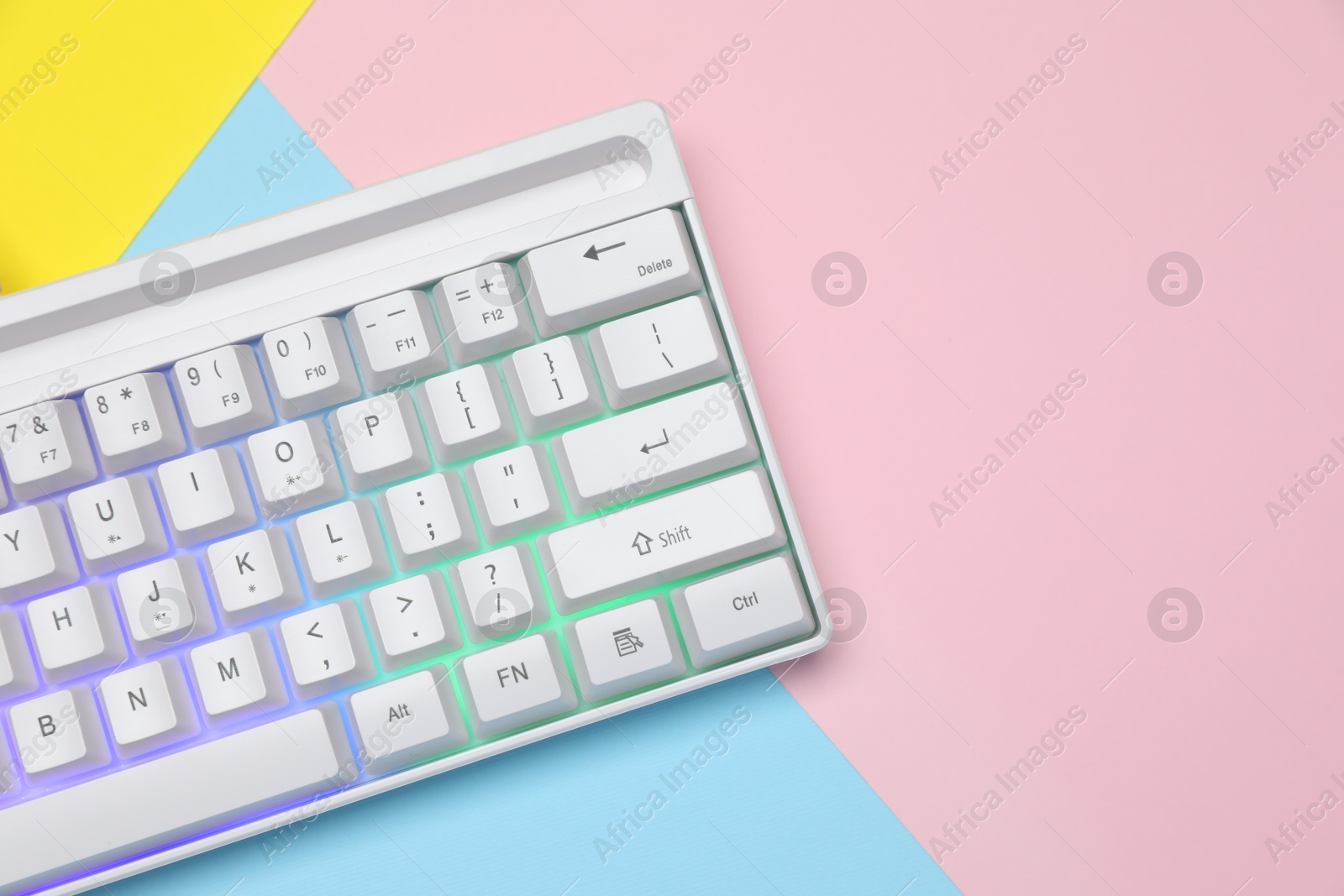 Modern white keyboard with RGB lighting on color background, top view. Space for text Photo of Modern white keyboard with RGB lighting on color background, top view. Space for text