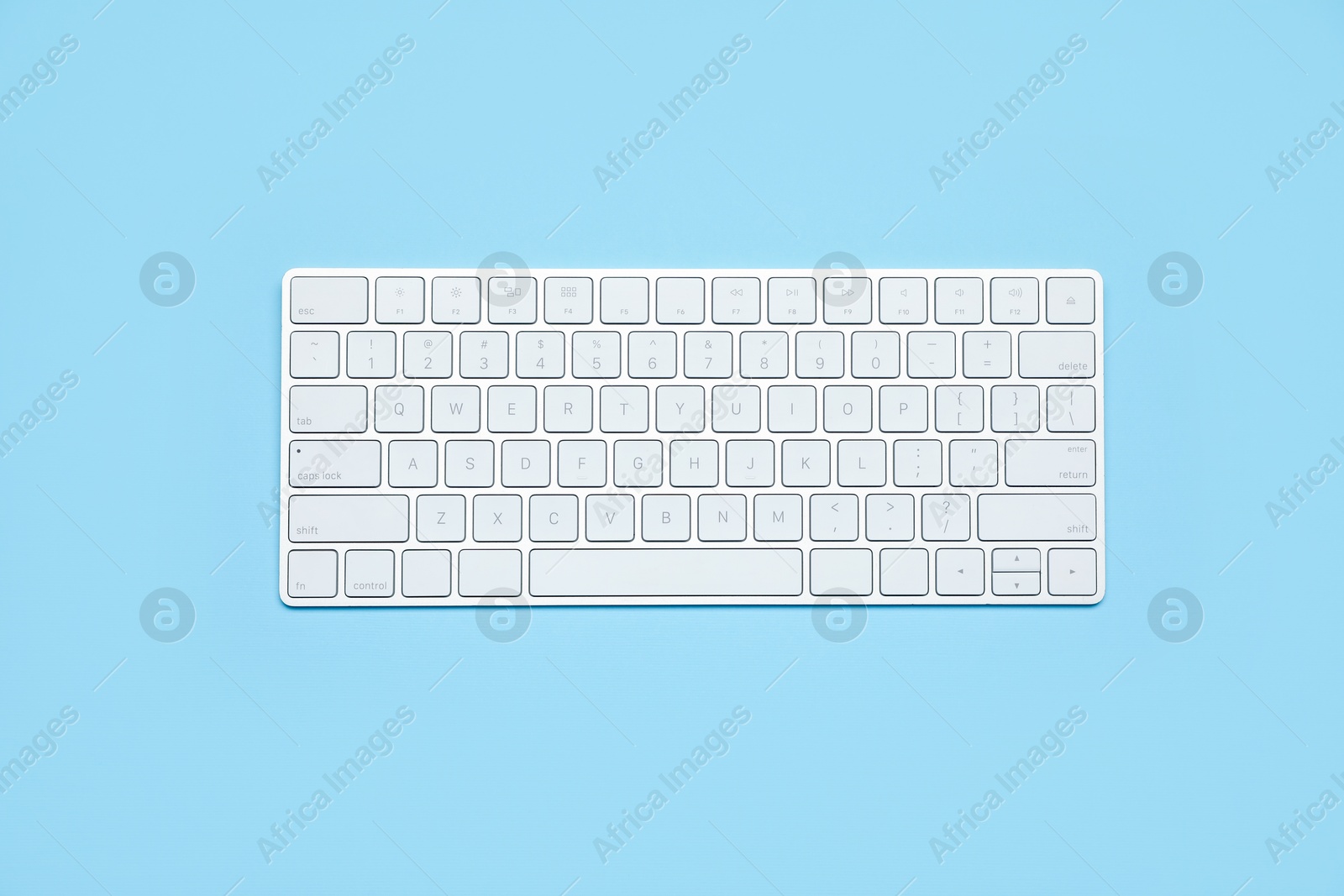 Photo of Modern white wireless keyboard on light blue background, top view