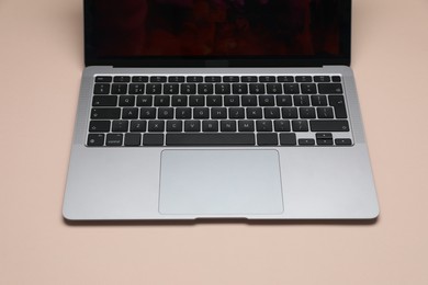 Photo of Modern laptop with keyboard on beige background, closeup