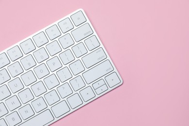 Photo of Modern white wireless keyboard on pink background, top view. Space for text