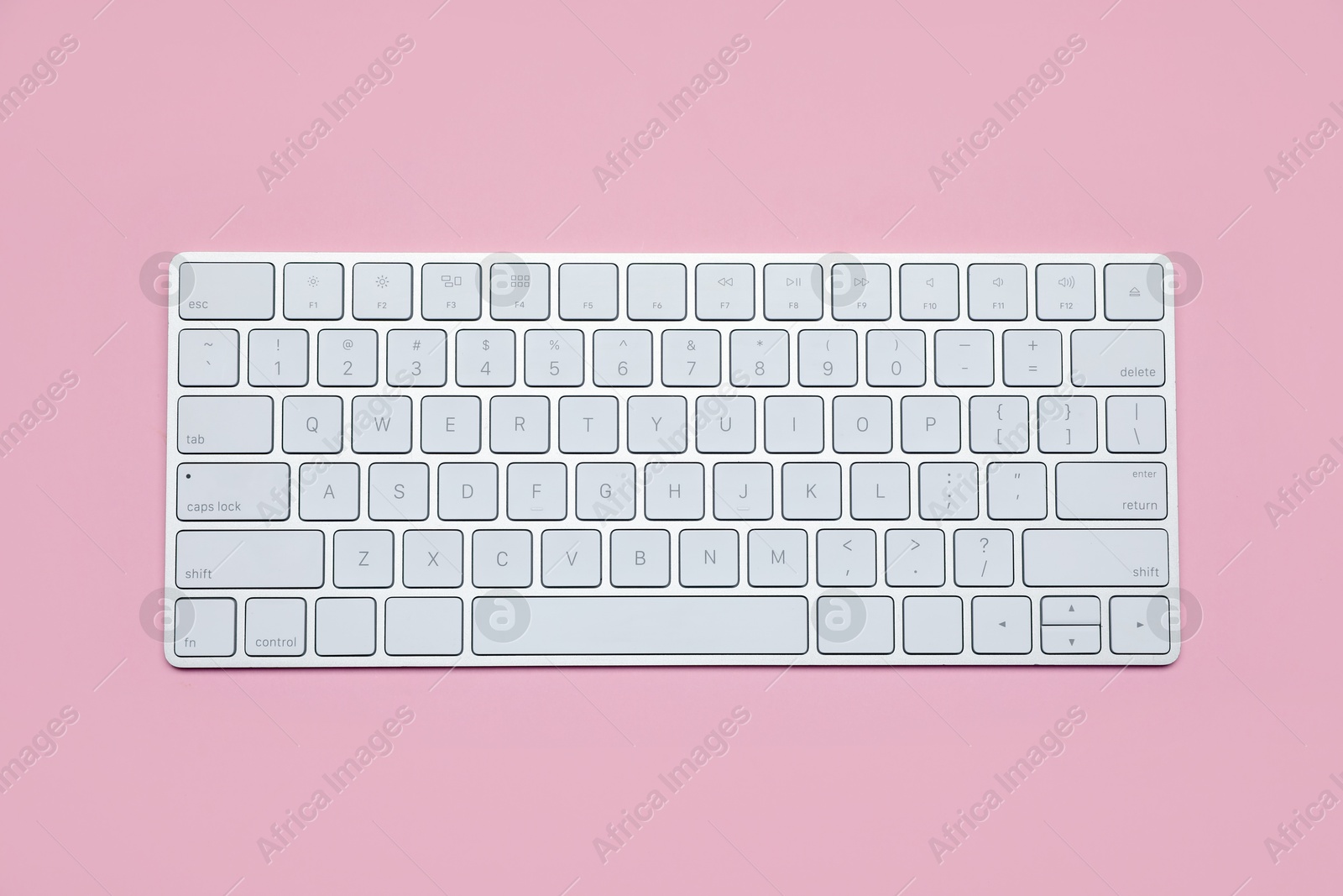 Photo of Modern white wireless keyboard on pink background, top view