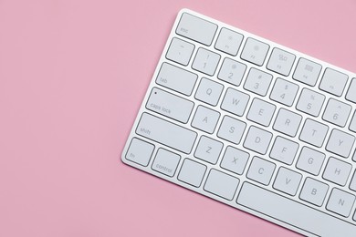 Photo of Modern white wireless keyboard on pink background, top view. Space for text