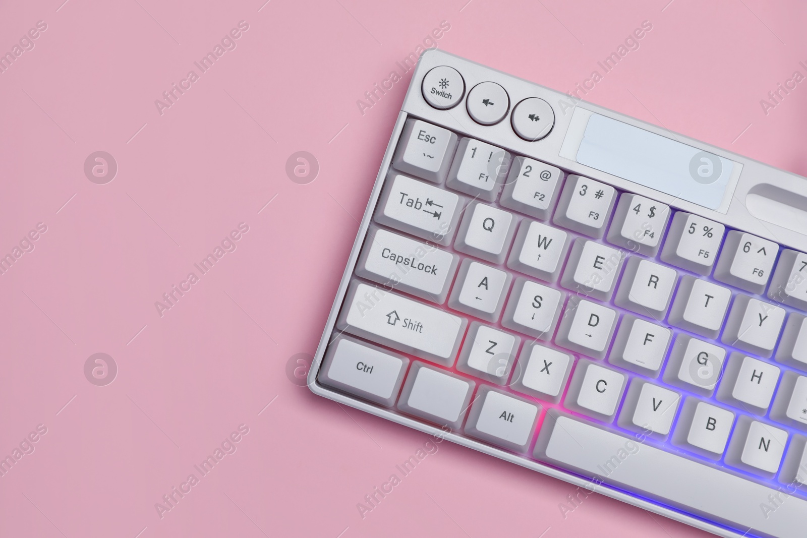 White keyboard with RGB lighting on pink background, top view. Space for text Photo of White keyboard with RGB lighting on pink background, top view. Space for text