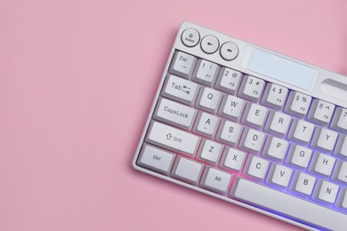 Photo of White keyboard with RGB lighting on pink background, top view. Space for text