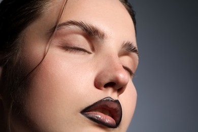 Photo of Beautiful young woman with black lip liner on light grey background, closeup