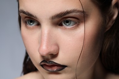 Photo of Beautiful young woman with black lip liner on light grey background, closeup