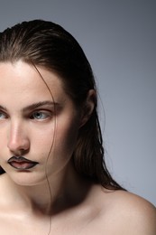 Photo of Beautiful young woman with black lip liner on light grey background, closeup