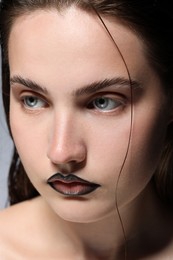 Photo of Beautiful young woman with black lip liner on light grey background, closeup