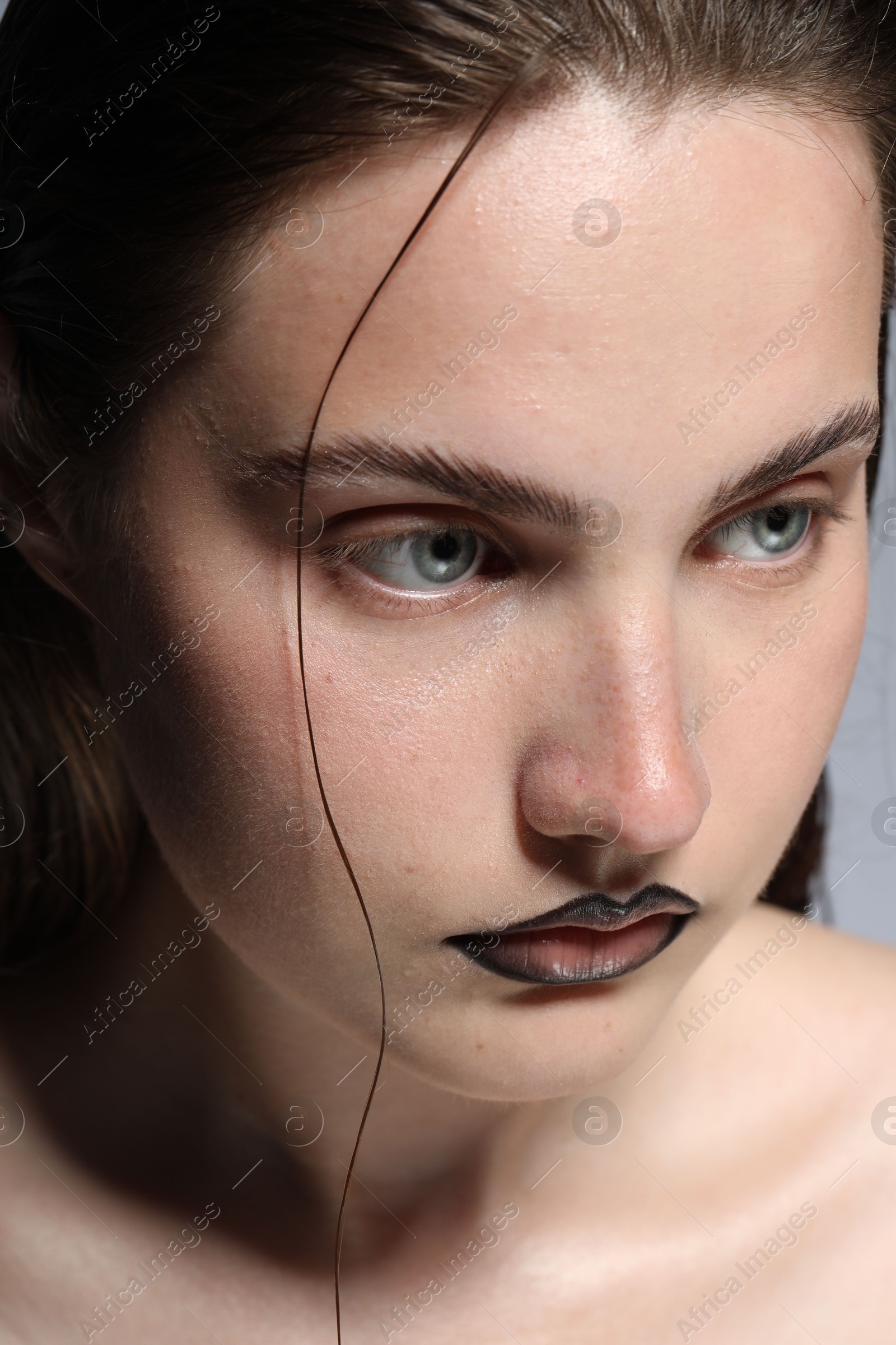 Beautiful young woman with black lip liner on light grey background, closeup Photo of Beautiful young woman with black lip liner on light grey background, closeup