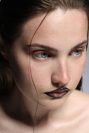 Photo of Beautiful young woman with black lip liner on light grey background, closeup