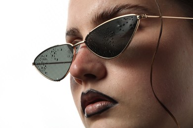 Photo of Beautiful young woman with black lip liner wearing wet sunglasses on white background, closeup