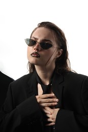 Photo of Beautiful young woman with black lip liner wearing wet sunglasses on white background