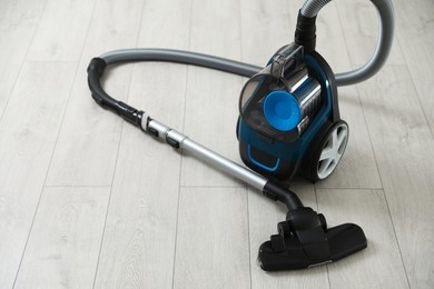 Photo of One vacuum cleaner on wooden floor. Household appliance