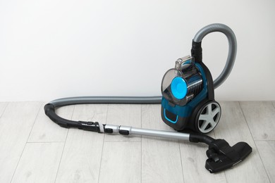 Photo of One vacuum cleaner on floor near white wall