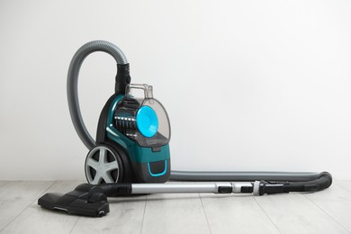 Photo of One vacuum cleaner on floor near white wall