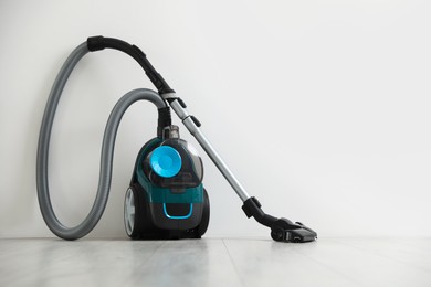 Photo of One vacuum cleaner on floor near white wall
