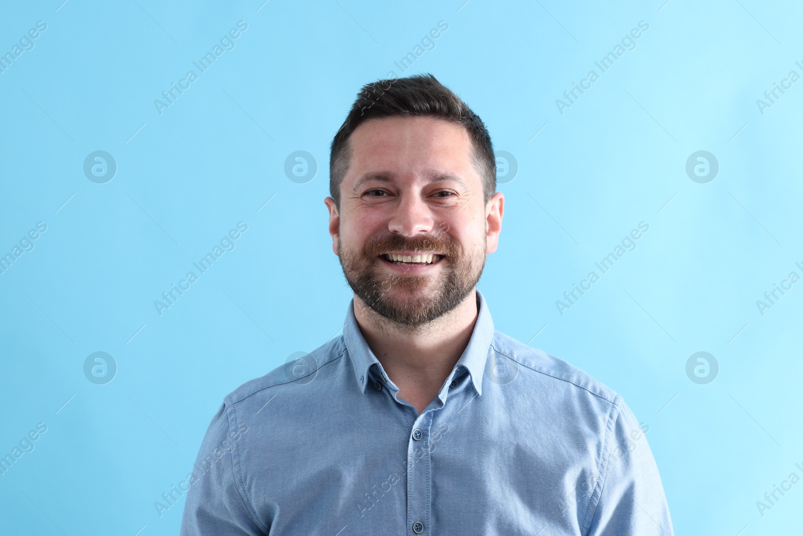 Photo of Handsome man laughing on light blue background