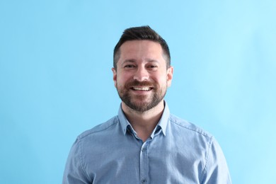 Photo of Handsome man laughing on light blue background