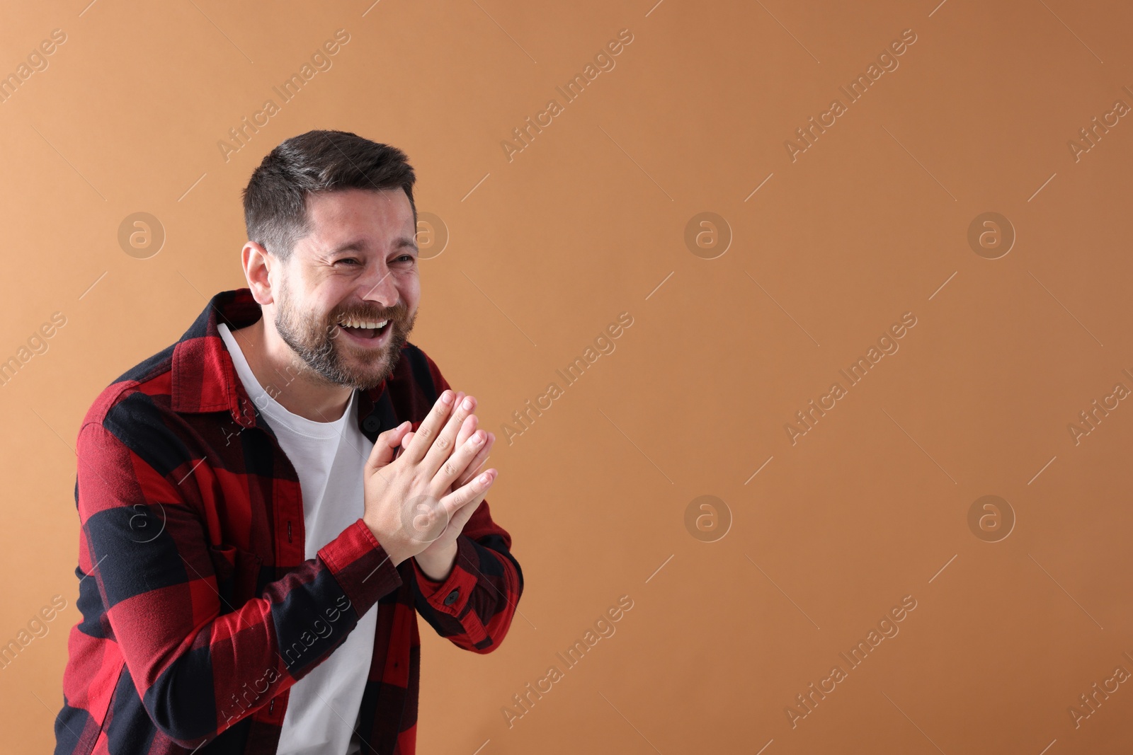 Photo of Handsome man laughing on dark beige background, space for text