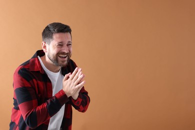Photo of Handsome man laughing on dark beige background, space for text