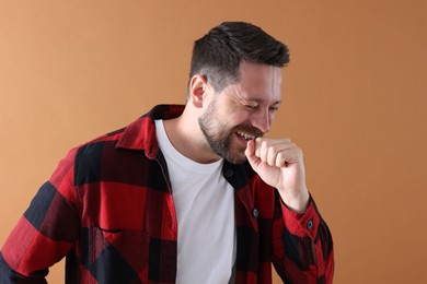 Photo of Handsome man laughing on dark beige background