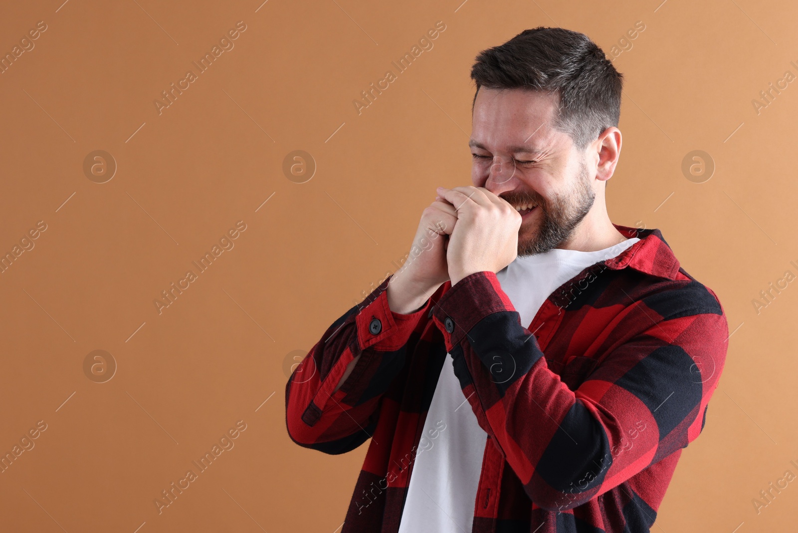 Photo of Handsome man laughing on dark beige background, space for text