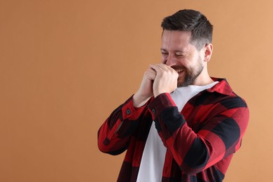 Photo of Handsome man laughing on dark beige background, space for text
