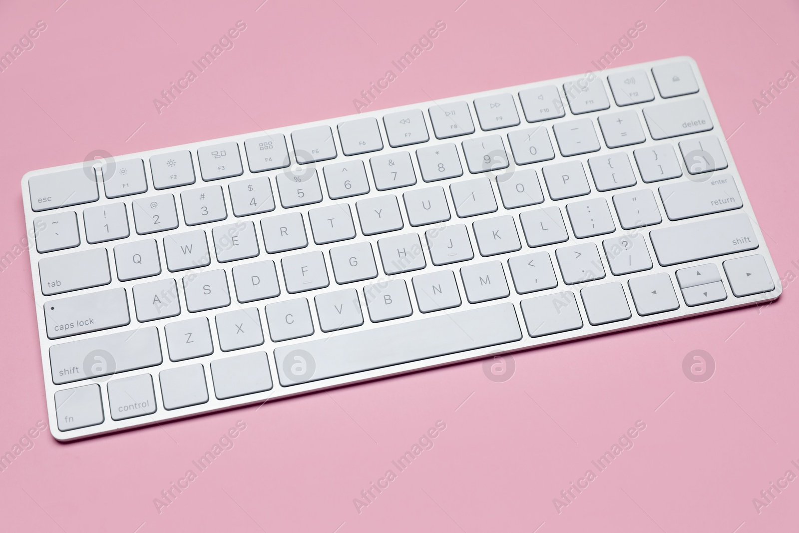 Modern white wireless keyboard on pink background Photo of Modern white wireless keyboard on pink background