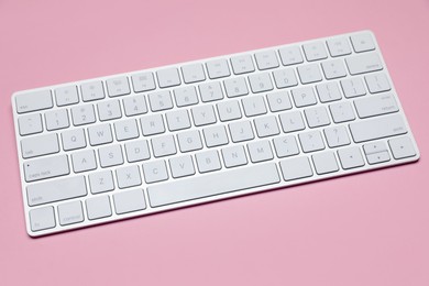 Photo of Modern white wireless keyboard on pink background