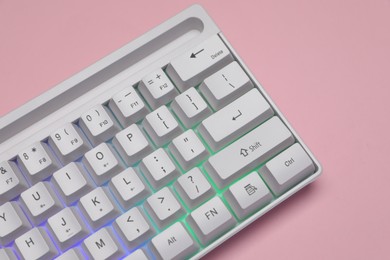 Photo of White keyboard with RGB lighting on pink background, top view